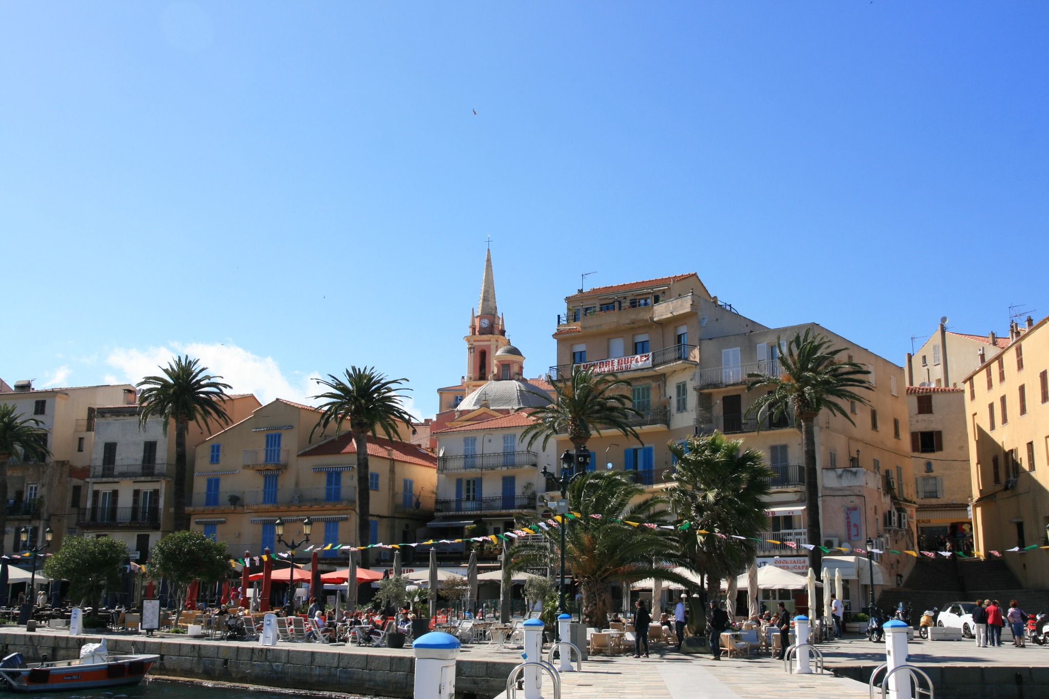 Place animée de Calvi avec palmiers et terrasses